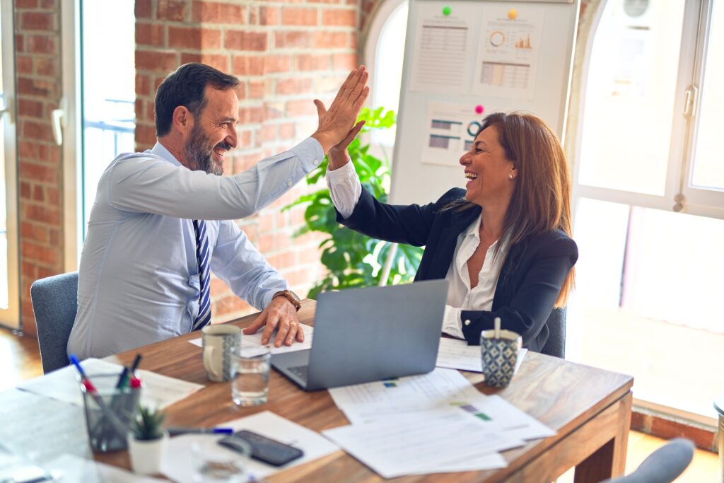 Two office people high-fiving the success of their New Year's marketing campaigns.